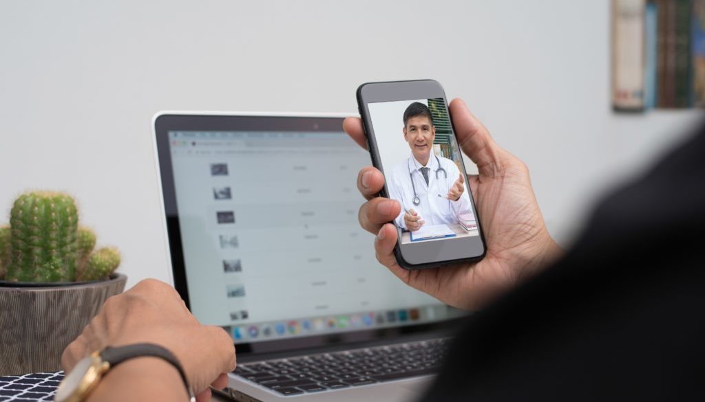 student using telemedicine on their cellphone while working at desk