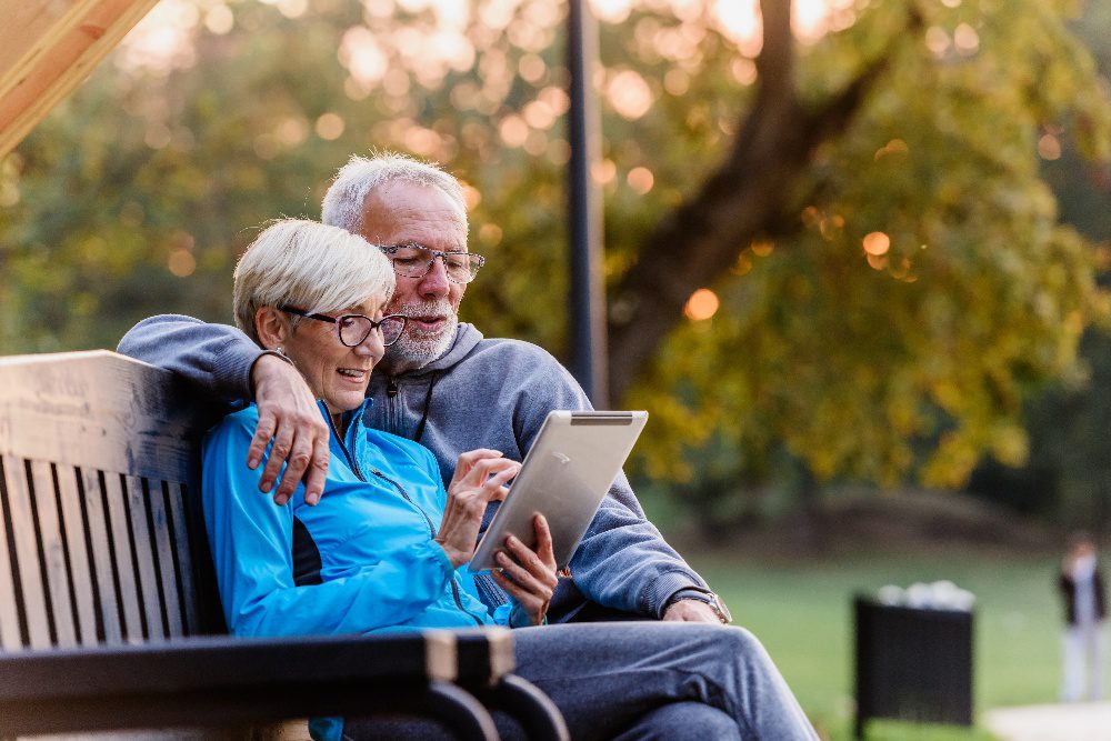 elderly couple sitting together on bench