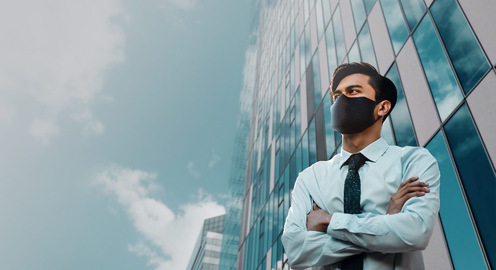 man wearing mask in front of office building