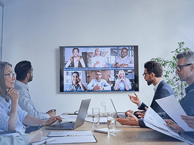 employees sitting in office with additional employees remotely in meeting via the screen