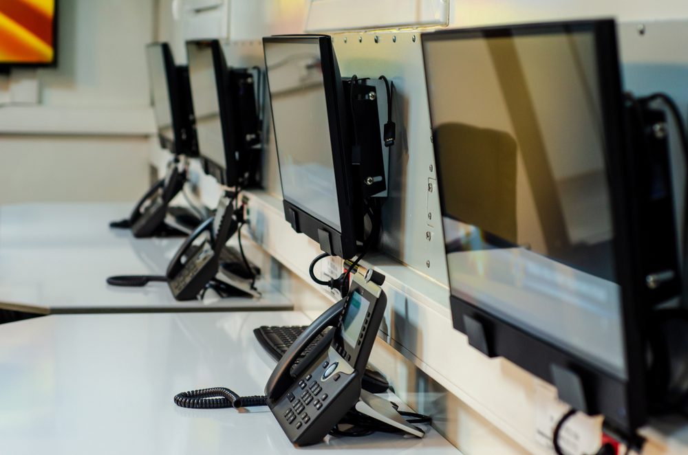 desk in emergency call center with a row of phones and computers