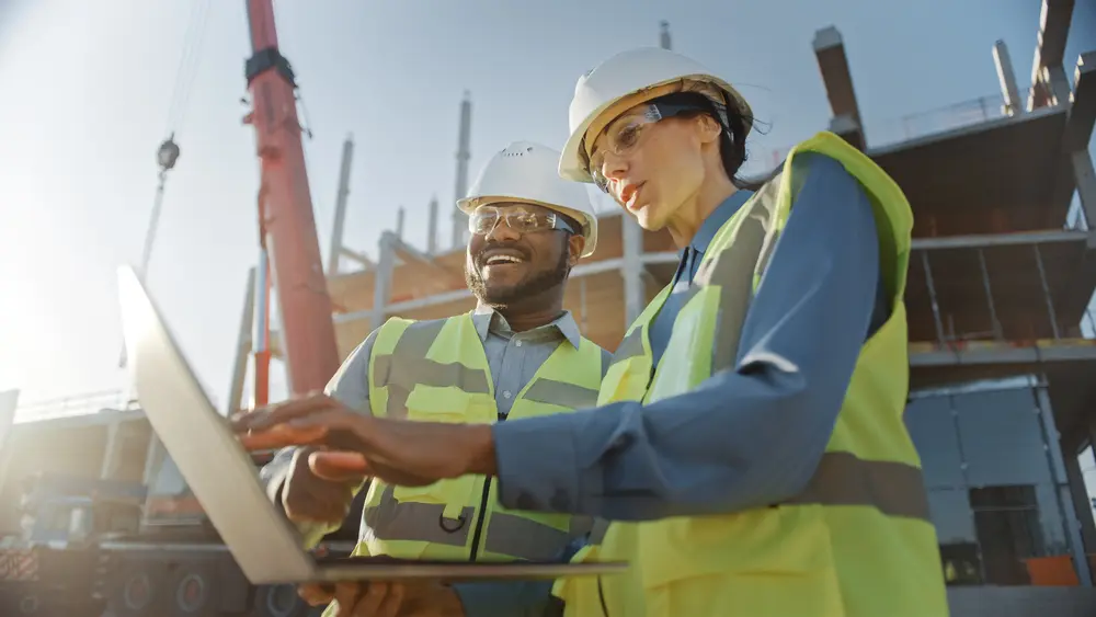 construction workers looking at computer on a job site