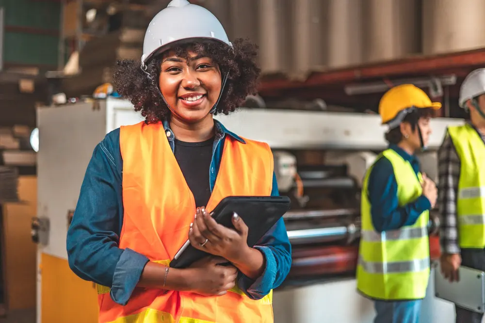 woman wearing vest and hard hat in manufacturing facility